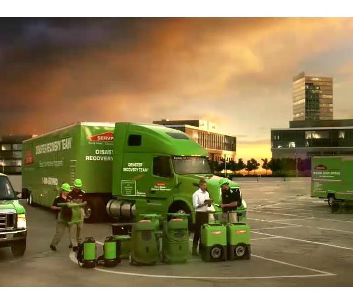 A fleet of SERVPRO vehicles in front of a smokey sky